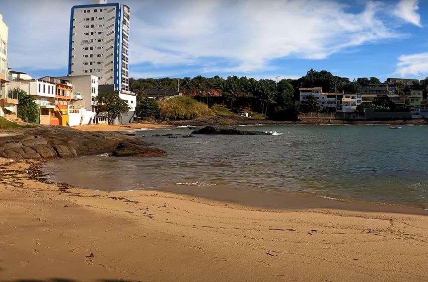 Praia do Valad&atilde;o, em Guarapari, com faixa de areia pequena, pedras e casas constru&iacute;das &agrave; beira-mar