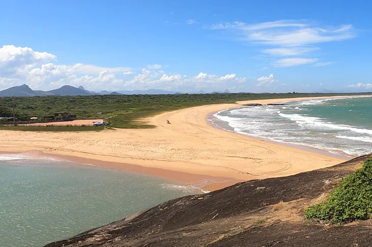 Vista do alto da Pedra de Setiba Pina, com a Praia de Setib&atilde;o, a restinga e as montanhas ao fundo, em Guarapari