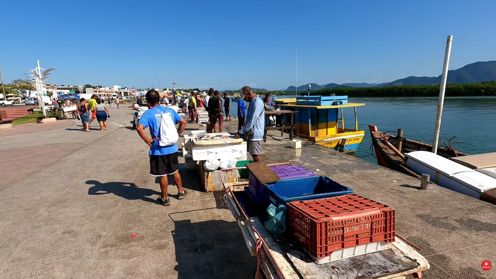 Pescadores e clientes no Cais de Guarapari, com caixas de peixe no cal&ccedil;ad&atilde;o em frente aos barcos