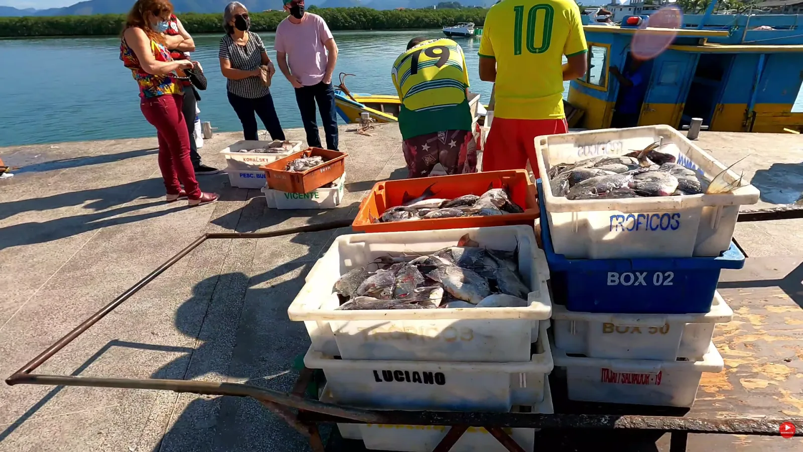 Caixas cheias de pero&aacute; &agrave; venda no Cais de Guarapari, com clientes escolhendo o peixe
