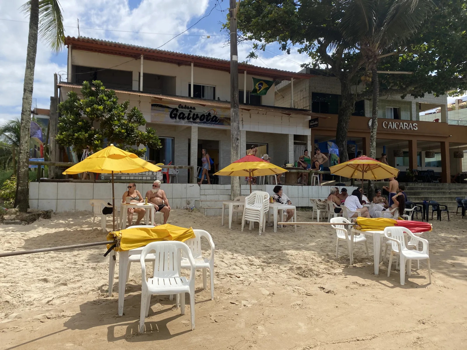 Fachada da Cabana Gaivota com mesas e guarda-s&oacute;is amarelos na areia da Praia de Santa M&ocirc;nica, Guarapari