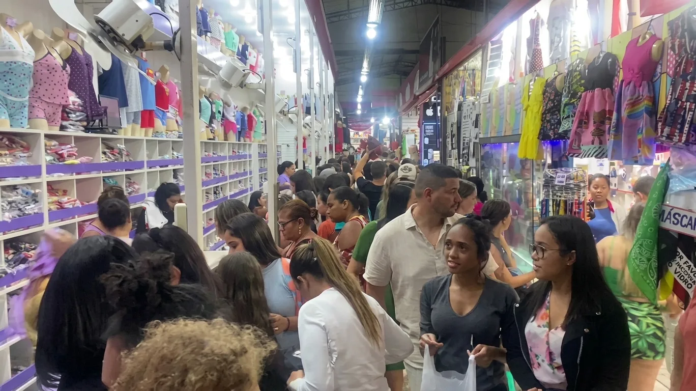 Corredor lotado de pessoas entre lojas de pijamas e roupas no Centro Comercial da Onda, na Praia do Morro, em Guarapari