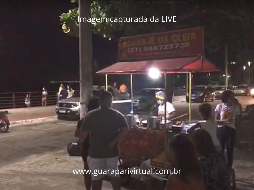 Carrinho de acaraj&eacute; iluminado na orla do Centro de Guarapari &agrave; noite, com clientes em volta