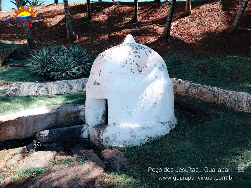 Po&ccedil;o dos Jesu&iacute;tas, em Guarapari: pequena constru&ccedil;&atilde;o branca em forma de c&uacute;pula sobre a grama, cercada por mureta decorada com conchas