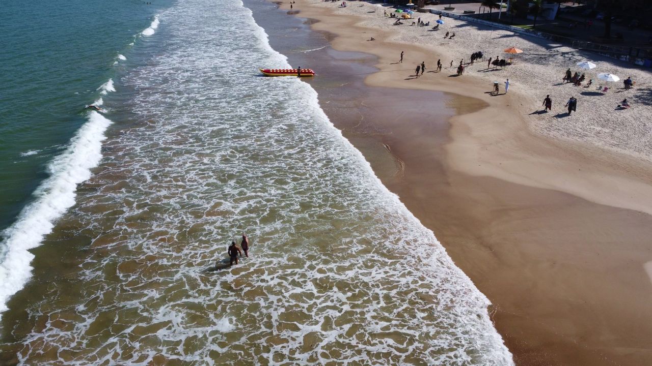 Vista a&eacute;rea da faixa de areia e do mar em Guarapari, com banhistas na beira da praia