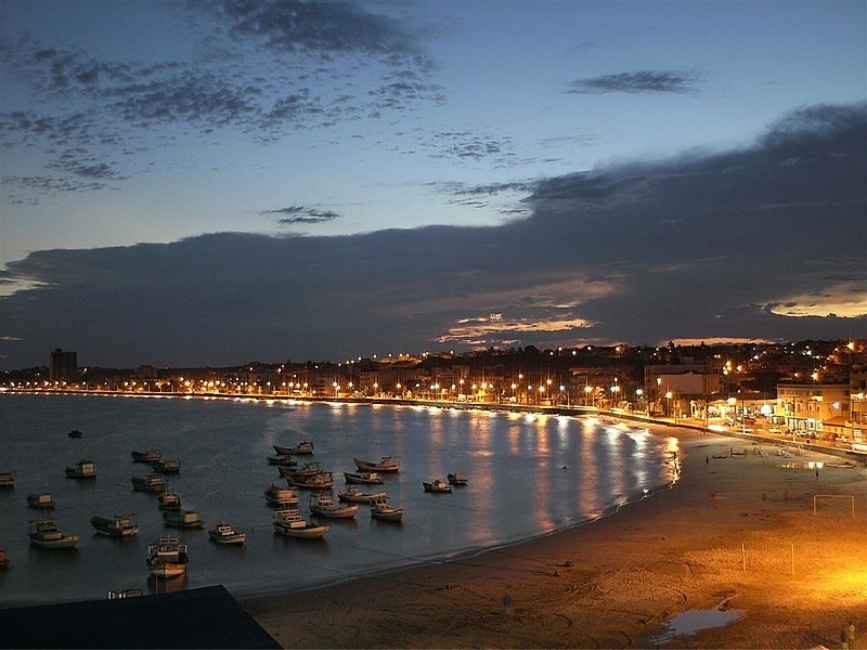 Orla de Marata&iacute;zes &agrave; noite, com barcos de pesca na enseada e as luzes da cidade