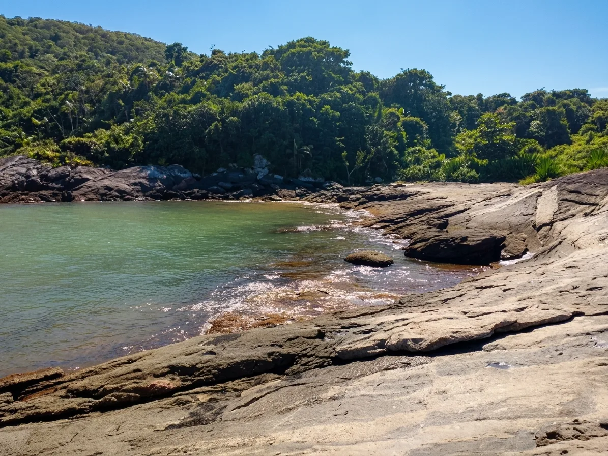 Pedras lisas e &aacute;gua verde-clara no canto da Praia do Ermit&atilde;o, em Guarapari