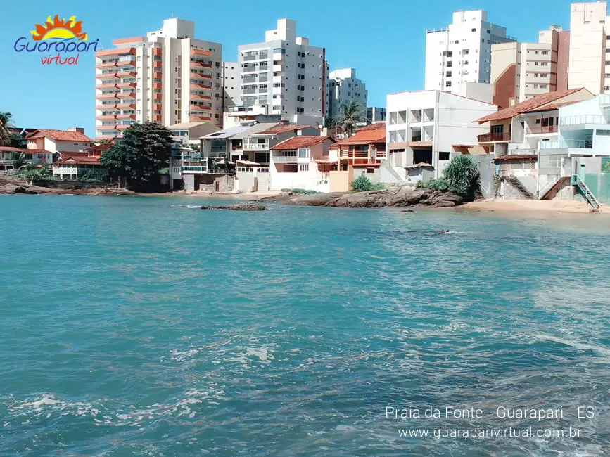 Praia da Fonte, no Centro de Guarapari, vista do mar, com casas e pr&eacute;dios atr&aacute;s da pequena faixa de areia