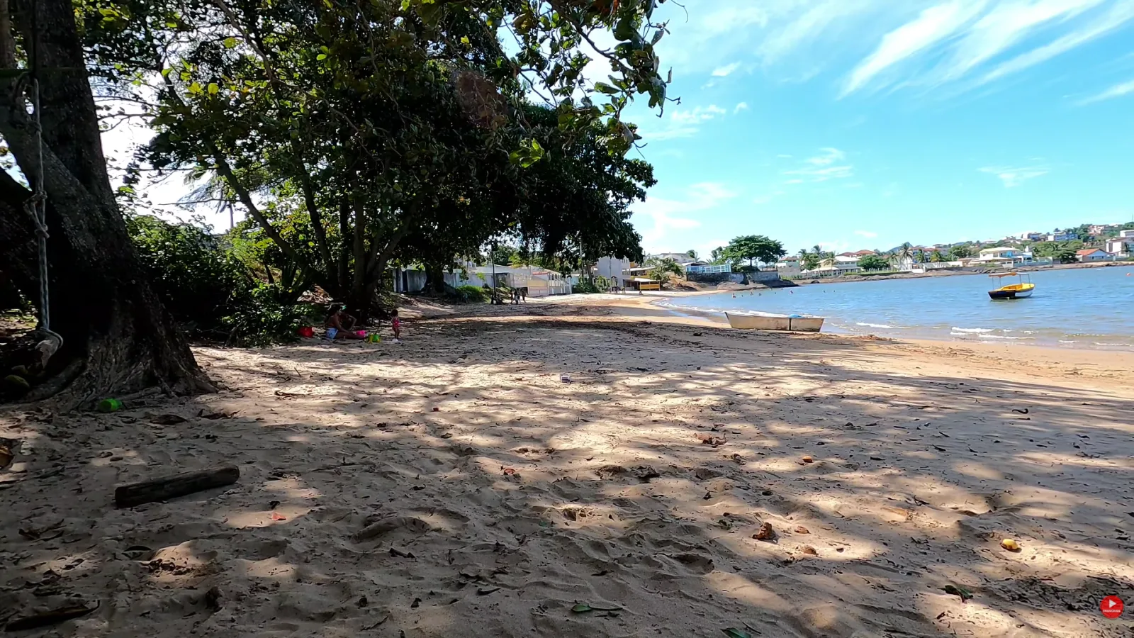 Sombra de &aacute;rvores grandes na areia da Praia do Boi&atilde;o, em Peroc&atilde;o, Guarapari, com barcos na ba&iacute;a