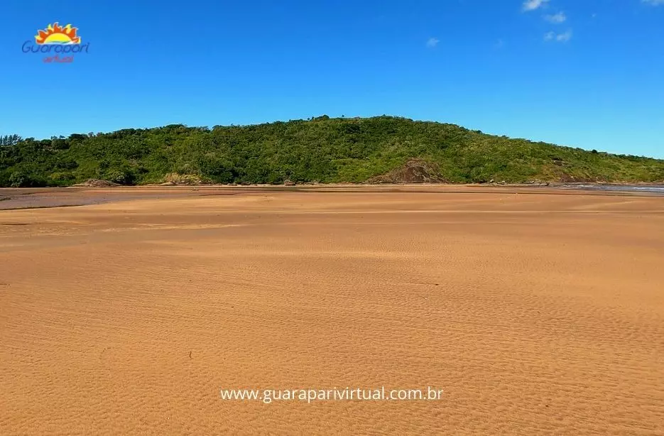 Grande faixa de areia descoberta na mar&eacute; baixa no final da Praia de Santa M&ocirc;nica, com o Morro do Una ao fundo, em Guarapari